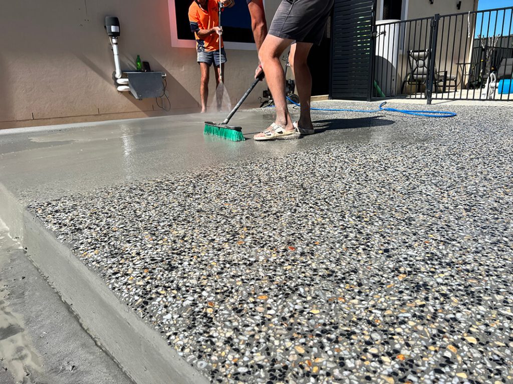 washing the surface of the concrete, revealing the beautiful aggregate beneath